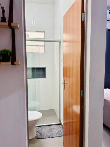 a bathroom with a toilet and a glass door at VOER - BR Flat Hospedaria in Sete Lagoas