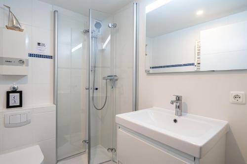 a white bathroom with a sink and a shower at Apartment MeerZeit in Büsum