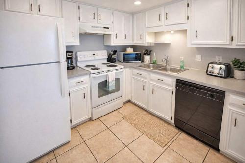 a kitchen with white cabinets and a white refrigerator at Bay View Great Deck Pool 2 levels & 3 bedr condo in South Padre Island