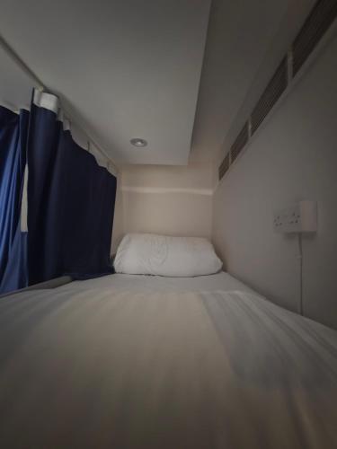 a white bed in a room with a blue curtain at Muscat Beach Hostel in Muscat