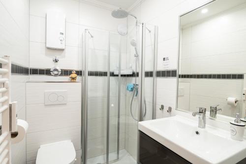 a white bathroom with a shower and a sink at Encore Seaside in Büsum