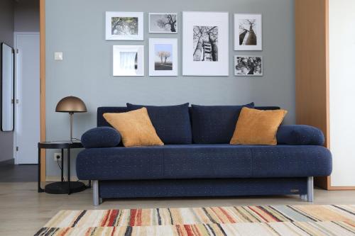a blue couch in a living room with pictures on the wall at Vita Apartmanok in Hévíz
