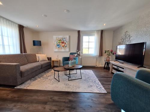 a living room with a couch and a flat screen tv at Aparthotel Ons Epen in Epen