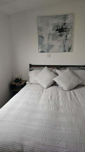a white bed with two pillows and a painting above it at 16 farmfield in Skipsea