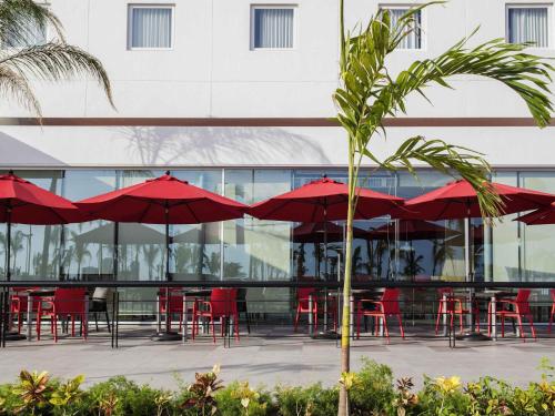 a group of red tables and chairs with red umbrellas at Ibis Mazatlan Marina in Mazatlán