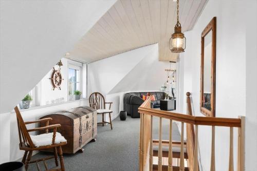 a living room with a staircase and a room with chairs at BV277-Blavand-Klitvej-4 in Blåvand