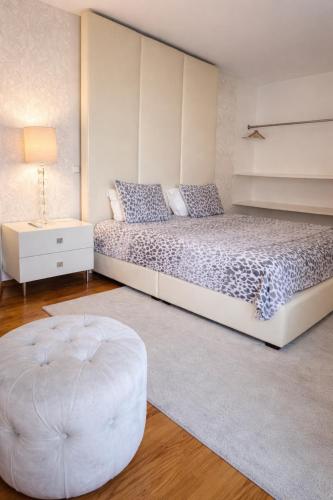 a bedroom with a large bed and a ottoman at Mindelo apart in front of the best beach of North Portugal in Mindelo