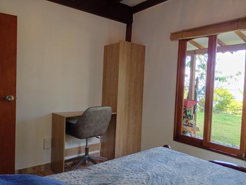 a bedroom with a bed and a chair and a window at Rural Cabin Among Clouds Támesis in Támesis