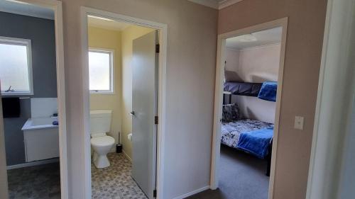 a bathroom with a bedroom with a bed and a toilet at Hooked On Tiki in Coromandel Town