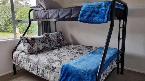 a bedroom with two bunk beds and a couch at Hooked On Tiki in Coromandel Town