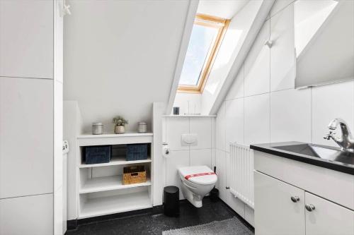 a white bathroom with a toilet and a sink at BV100-Blavand-Blavandvej-53-C in Blåvand