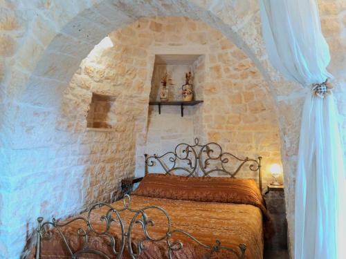 a bedroom with a bed in a stone wall at B&B La Rosa dei Trulli Alberobello in Alberobello