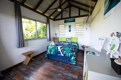 a bedroom with a bed in a room with windows at Fare Te Ava Iti in Teahupoo
