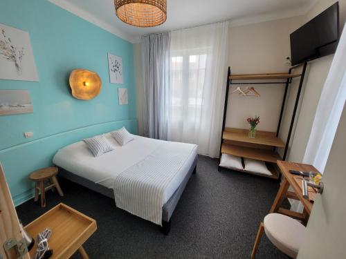 a bedroom with a white bed and a blue wall at La Villa Rose-Marie in Saint-Brevin-les-Pins