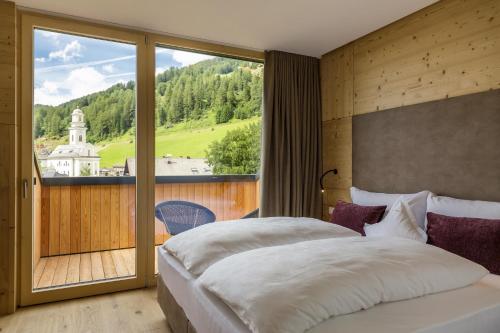 sypialnia z dużym łóżkiem i dużym oknem w obiekcie Hotel Strobl w mieście Sesto