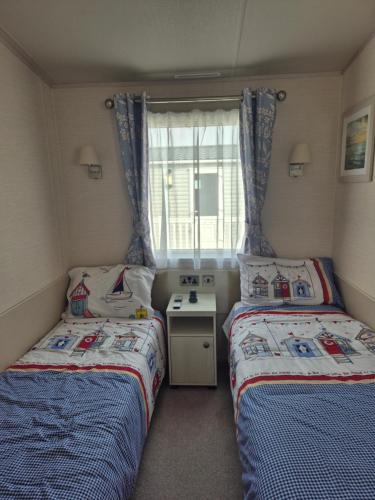 two beds in a small room with a window at Tower View Retreat, Haven Marton Mere in Blackpool
