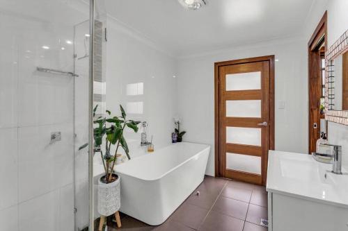 a white bathroom with a tub and a plant at 31 The Rocks in Stanthorpe