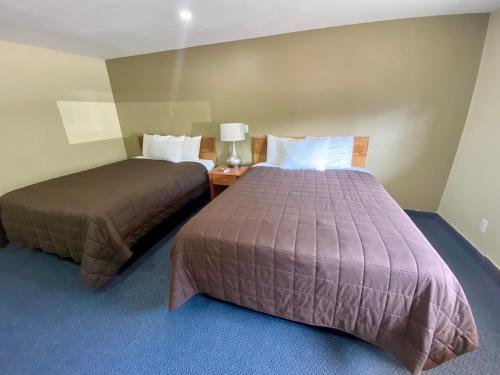 a hotel room with two beds and a table with a lamp at Kings Inn Orillia in Orillia