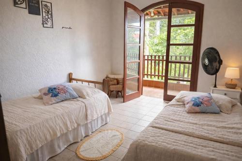 two beds in a room with a balcony at Casinha beira praia Gaivota ,há 2 minutos da praia in Itanhaém