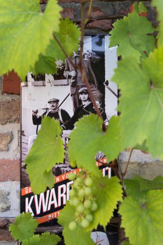 a sign on the side of a brick wall with green leaves at Oud Gemeentehuis in Poelkapelle