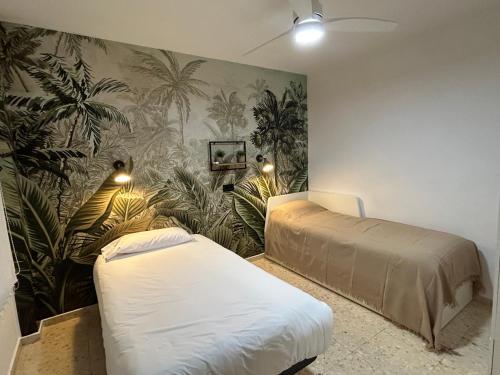 a bedroom with two beds and a mural of palm trees at EL PARQUE II - Parking gratuito cercano in Ciudad Real
