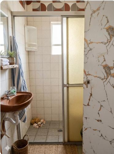 a bathroom with a sink and a shower backdoor at Casinha beira praia Gaivota ,há 2 minutos da praia in Itanhaém