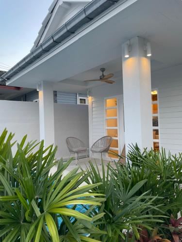 a white house with two chairs and plants at Samui Serenity 63 Pool Villa in Choeng Mon Beach