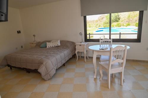 a bedroom with a bed and a table and a window at Aguamansa Apart in Potrero de los Funes