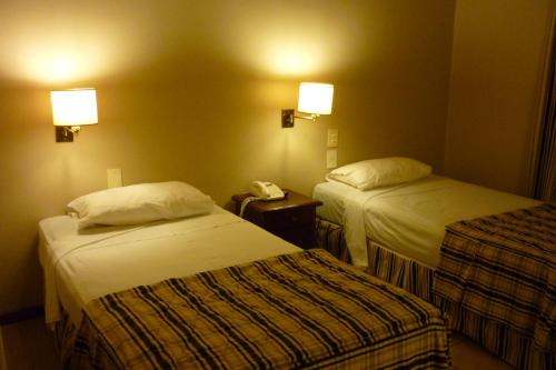 a hotel room with two beds and a phone at Marcopolo Suites Iguazu in Puerto Iguazú