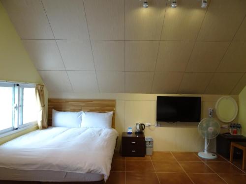 a bedroom with a bed and a flat screen tv at Goose House in Yung-an-ts'un