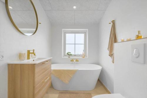 a bathroom with a tub and a sink and a mirror at 1159-Ringkobing-Anders-Juhls-Vej-13 in Søndervig