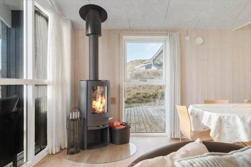 a fireplace in a living room with a table and a window at 135-Ringkobing-Sortebaerdalen-51 in Kryle