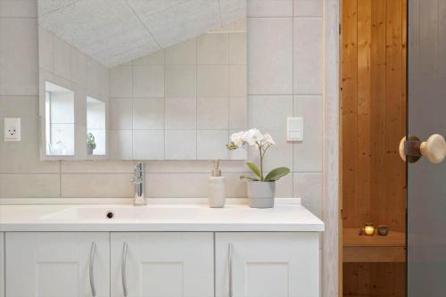 a white bathroom with a sink and a mirror at 135-Ringkobing-Sortebaerdalen-51 in Kryle