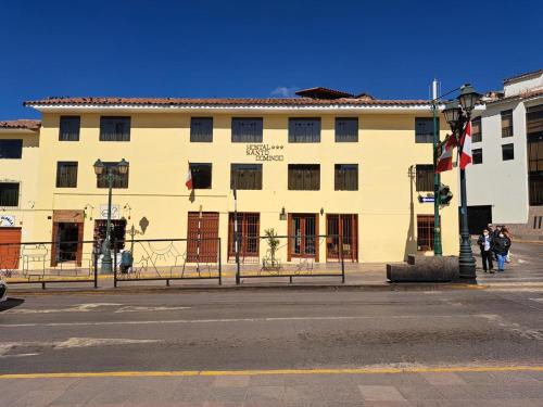 a large white building on a city street with people walking in front at Hostal Santo Domingo in Cusco