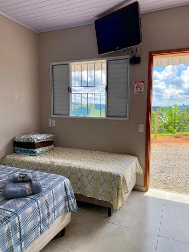 a bedroom with two beds and a flat screen tv at Chalés Sonho Meu in Munhoz
