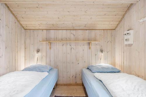 two beds in a room with wooden walls at 160-Ringkobing-Granalle-17 in Nørby
