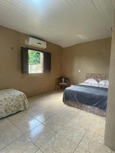 a bedroom with two beds and a window with a fan at Sitio Resenha in Caucaia