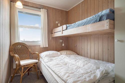 a bedroom with two bunk beds and a chair at 208-Ringkobing-Fladsbjergvej-226 in Klegod