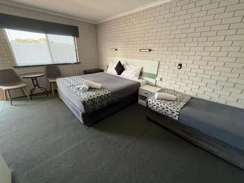 a bedroom with two beds and a table and chairs at Surf Beach Motel Tweed in Tweed Heads