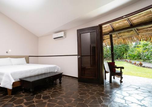 a bedroom with a bed and a chair and a window at Aranwa Sarapiquí Rainforest Lodge in Sarapiquí