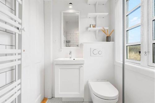 a white bathroom with a toilet and a sink at 1154-Ringkobing-Nordsovej-50 in Søndervig