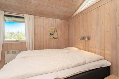 a large bed in a room with wooden walls at 078-Ringkobing-Rorsangervej-11 in Nørby