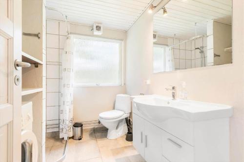 a white bathroom with a toilet and a sink at 095-Ringkobing-Risbjergvej-12 in Nørby