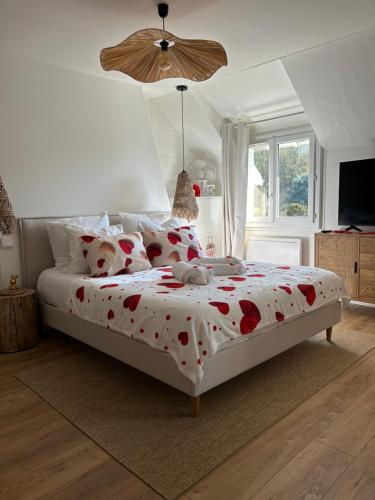a bedroom with a large bed with red flowers on it at Parenthèse entre forêt et château in Pierrefonds