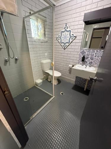 a bathroom with a shower and a toilet and a sink at Surf Beach Motel Tweed in Tweed Heads