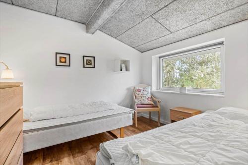 a bedroom with a bed and a window and a chair at 286-Ringkobing-Vestklitvej-14 in Klegod