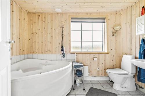 a bathroom with a white tub and a toilet at 1101-Ringkobing-Rorsangervej-8 in Nørby