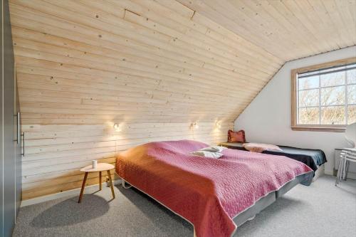 a bedroom with two beds and a wooden wall at 1101-Ringkobing-Rorsangervej-8 in Nørby