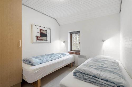 a bedroom with two beds and a window at 113-Ringkobing-Ahornalle-16 in Nørby