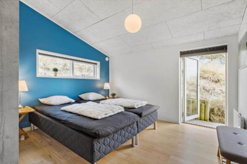 a large bed in a room with a blue wall at 1149-Ringkobing-Holmsborgvej-32 in Søndervig